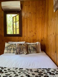 a bedroom with a bed with wooden walls and a window at Onda Azul Back Unit A & B in Ponta do Ouro
