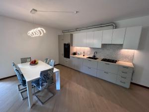 a kitchen with white cabinets and a white table and a table and chairs at Rosa dei Venti - Como Lake House in Valmadrera
