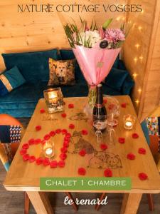 a coffee table with a vase of flowers and a bottle of wine at Nature Cottage Vosges in Anould +34 photos
