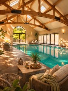an indoor swimming pool with a table and chairs at Cha Cha de Loup-B&B-Vakantiewoning met verwarmd binnenzwembad en groot zonneterras in de Ardennen in Rendeux