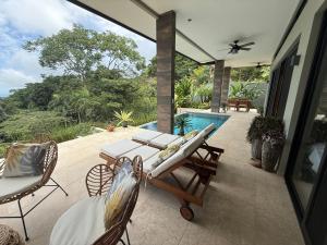 a patio with a table and chairs and a swimming pool at Villa Montemar Ocean and Mountain Views in Platanillo