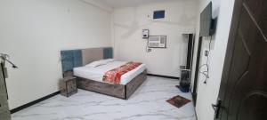 a small bedroom with a bed and a tiled floor at Anusthan Hotel in Ūnchāhar