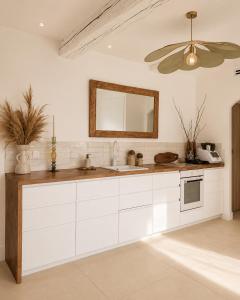 a white kitchen with a sink and a mirror at Villa Boho Cassis in Cassis