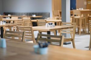an empty restaurant with wooden tables and chairs at Hotel Spenerhaus - neu und vollklimatisiert in allen Zimmern in Frankfurt
