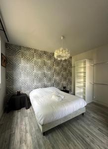 a bedroom with a white bed and a wall at Pause détente à Aubenas in Aubenas