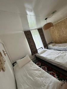 a small room with two beds and a window at Gulazyk guest house in Bokonbayevo