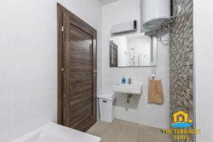 a bathroom with a sink and a wooden door at The Terraces Seafront Getaway Malta 3 Bedroom Apartment in St. Paul's Bay +25 photos