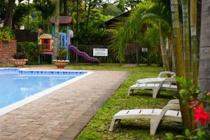 a pool with two white benches next to a playground at Flamingo Holiday Flats in St Lucia