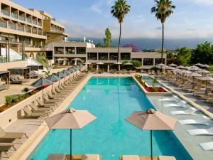 a swimming pool with chairs and umbrellas in front of a hotel at Iolida Corfu Resort by Smile Hotels in Dassia