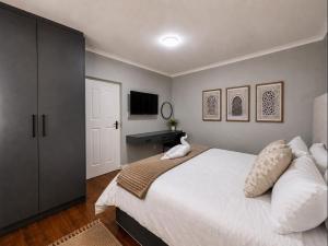 a bedroom with a large white bed and a television at Pecan Tree Lodge in Cape Town