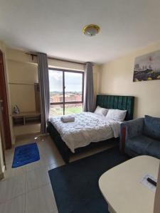 a bedroom with a bed and a couch and a window at Majestic studio in Rungiri