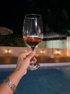 a person holding a wine glass in front of a pool at Flat Aeroporto - Estrada do coco - Lauro de Freitas M in Lauro de Freitas