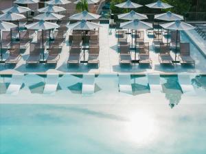a pool with chairs and tables and umbrellas at Iolida Corfu Resort by Smile Hotels in Dassia