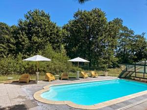 a swimming pool with chairs and umbrellas at Le Fourneau Rond in Soings-en-Sologne