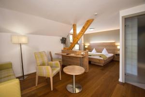 a bedroom with a bed and a table and chairs at Logis Hôtel-Restaurant Auberge Du Mehrbachel in Saint-Amarin