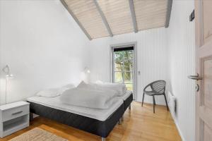 a white bedroom with a bed and a chair at BV225-Blavand-Blavandvej-5-E in Blåvand