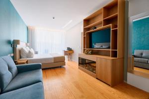 a room with a bed and a tv and a couch at Hotel Aquafalls in Caniçada