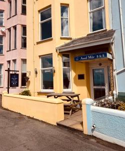 a yellow building with a picnic table in front of it at Awel Mor in Criccieth