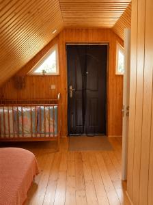 a bedroom with a black door in a wooden room at Peaceful Nature Cottage near Talsi with Hot Tub, Sauna & Pond, Camping Ives in Talsi