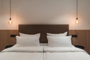 a bedroom with a bed with white pillows and lights at Egerner Chalet in Rottach-Egern