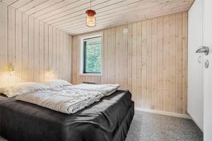 a bedroom with a bed in a room with wooden walls at LF14102-Roslev-Eskovvej-102 in Roslev