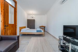 a living room with a bed and a television at Andreas Beachfront Hostel in Larnaca