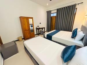 a hotel room with two beds and a window at Cozy Bay Hotel in Arugam Bay