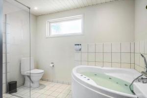 a bathroom with a tub and a toilet and a window at 393-Harboore-Fourmivej-10 in Harboør +23 photos