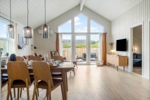 a dining room with a table and chairs and a living room at 393-Harboore-Fourmivej-10 in Harboør