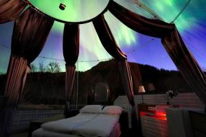 a bedroom with a tent with a view of the northern lights at Banpim Aroradome and jacusszy in Gravdal +20 photos