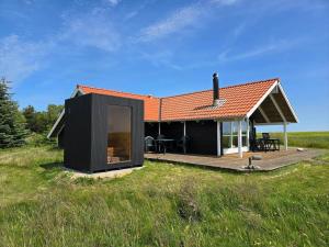 a black house with a deck in a field at LF10209-Thyholm-Markvejen-9 in Thyholm
