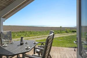 a table and chairs on a deck with a view of the ocean at LF10209-Thyholm-Markvejen-9 in Thyholm
