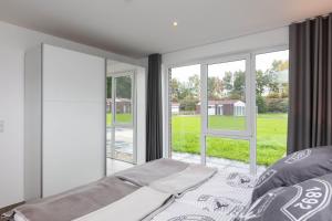 a bedroom with a bed and windows with a view at Haus 21 am See in Schüttorf