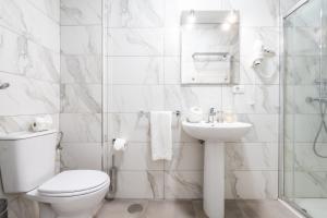 a white bathroom with a toilet and a sink at Los Menores Sea View in Adeje +62 photos