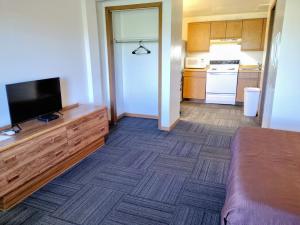 a small room with a television and a kitchen at Neva Jean Motel in Marshfield