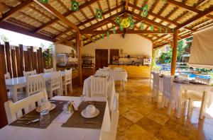 a dining room with white tables and white chairs at Pousada Windjeri in Jericoacoara