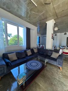a living room with a blue couch and a glass table at Kolkhi Guest House in Gonio