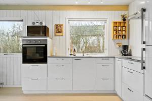 a kitchen with white cabinets and a microwave at LF11101-Struer-Blabaervej-12 in Struer +17 photos