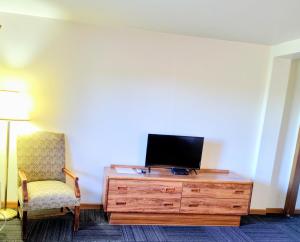 a room with a tv on a dresser with a chair at Neva Jean Motel in Marshfield