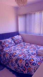 a bed with a floral comforter in a bedroom at 32 Hatton Guest House in Milton Keynes