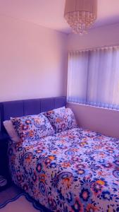 a bedroom with a bed with a floral comforter at 32 Hatton Guest House in Milton Keynes