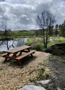 a wooden picnic table sitting next to a river at Chambres d'hôtes d'Isa in Bugeat