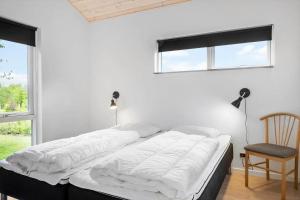 a bed in a bedroom with two windows and a chair at LF14344-Roslev-Folvigvej-44 in Roslev