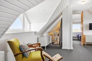 an attic room with a yellow chair and a bedroom at LF332-Hurup-Helligsovej-32 in Hurup