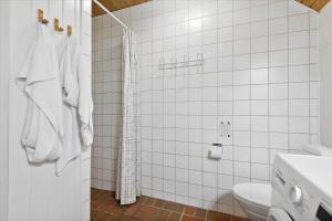a white tiled bathroom with a toilet and a shower at 0273-Romo-Lyngvejen-63-B in Høm +18 photos