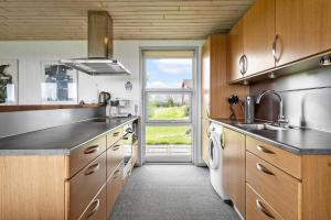 a kitchen with wooden cabinets and a large window at LF880-Snedsted-Over-Reese-11 in Snedsted