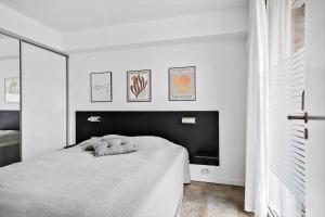 a white bedroom with a bed with a black headboard at 1160-Romo-Gulirisvej-160 in Høm