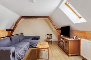 a living room with a couch and a tv at Le Café de l'Encloître in Beaumont-la-Ronce