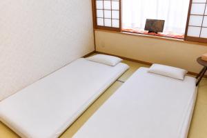 two beds in a room with two windows at Rabbit Island Inn in Mihara