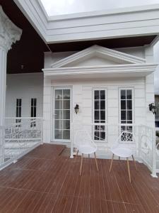 a porch with two chairs on a white house at Detara Homestay Syariah in Takengon